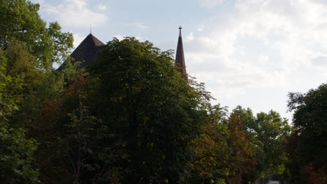 Driving-towards-old-baroque-Church-Tower-behind-trees-in-Budapest-City
