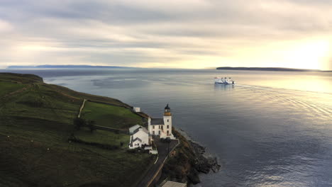 Spectacular-drone-shot-with-Ferry-departing-from-harbour-into-beautiful-sunset-passing-lighthouse