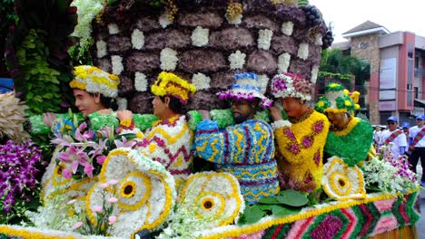 A-human-figure-and-a-caravan-made-of-colorful-flowers-are-on-parade