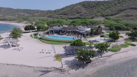 Aerial-orbiting-shot-of-Puntarena-hotel-resort-with-private-sandy-beach-in-Bani,-Dominican-Republic