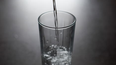 Cold-water-pours-into-glass-tumbler-creates-air-bubbles-in-slow-motion