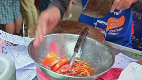 Cocinero-Callejero-Local-Haciendo-Ensalada-De-Verduras-Con-Tomates,-Zanahorias-Ralladas,-Cebollas,-Cilantro-Con-Algunas-Especias-Y-Condimentos-En-Un-Restaurante-De-Carretera-En-Bangkok,-Tailandia