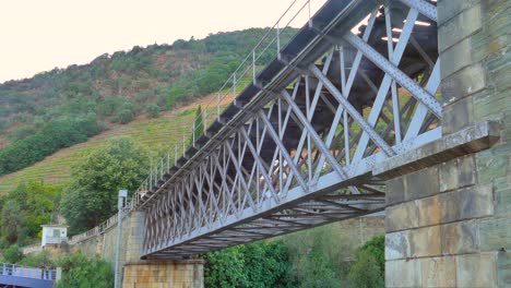 Struktur-Einer-Alten-Eisernen-Eisenbahnbrücke-Mit-Bergen-Im-Hintergrund-In-Pinhao,-Portugal