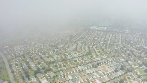 Aerial-drone-shot-slowly-descending-out-of-the-clouds-to-reveal-the-urban-sprawl-of-many-houses-in-The-Villages,-Florida