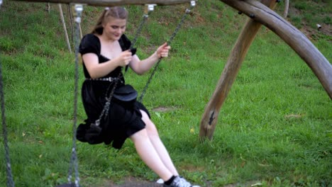 Girl-with-loose-hair-swings-on-a-swing,-carefree-youthful-joy-on-a-summer-day-in-the-park