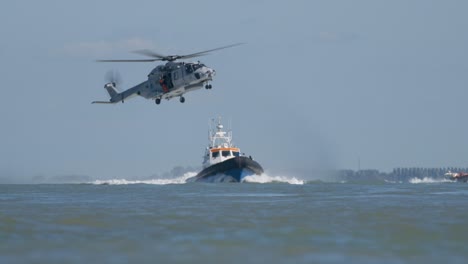 Taucher-An-Der-Winde-Unter-Dem-Marinehubschrauber-NH-90,-Der-über-Dem-Rettungsboot-Fliegt