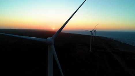 Drone-pedestal-rise-ascends-wind-turbine-shaft-and-blade-to-reveal-sunset,-northside-curacao