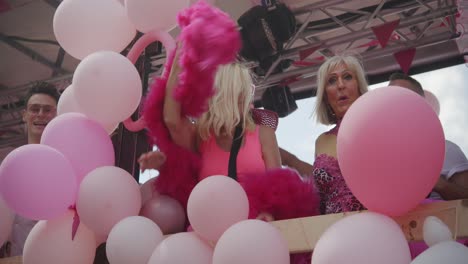 Women-and-a-dragqueen-in-pink-dresses-dancing-on-a-truck-during-the-Antwerp-Pride-Parade-2023-in-Belgium-with-pink-balloons