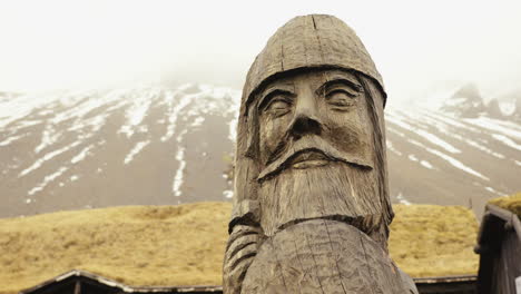 Gran-Escultura-De-Madera-De-Cabeza-Vikinga-Bajo-Montañas-Nevadas,-Disparo-De-Paralaje