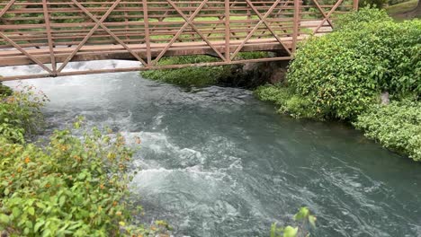 Agua-De-Manantial-Moviéndose-Rápidamente-Bajo-Un-Pequeño-Puente