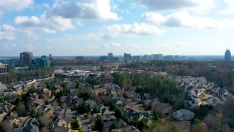 Aerial-drone-timelapse-looking-toward-downtown-Atlanta,-Georgia-from-above-Sandy-Springs-neighborhoods-as-clouds-pass-by-creating-shadows-over-the-homes