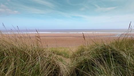 Luftvideoaufnahmen-Einer-Küstenstrandszene-Mit-Meer,-Sanddünen-Und-Tosenden-Wellen
