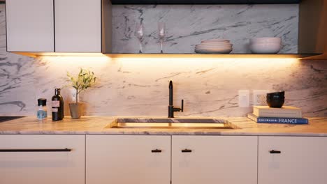 Panning-shot-of-a-well-lit,-white-and-bright-modern-kitchen-with-stylish-design