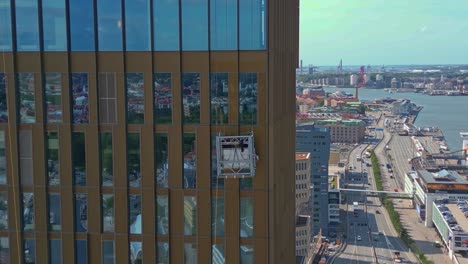 Aerial-of-window-cleaners-suspended-in-a-cradle-outside-of-the-Hotel-Draken,-Gothenburg,-Sweden