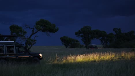 4-wheel-drive-jeep-with-glowing-headlamps-driving-through-tall-grass-on-a-night-Safari,-African-Wilderness-in-Maasai-Mara-National-Reserve,-Kenya,-Africa-Safari-adventure