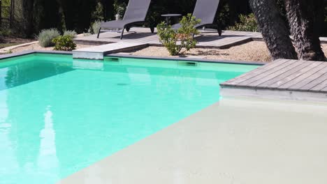 Slow-tilting-shot-revealing-sun-loungers-sitting-at-poolside-at-a-villa-in-Nimes