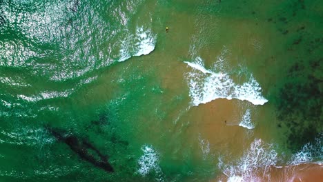 aerial-view-of-ocean,-crushing-waves,-surfers-and-beach,-4k
