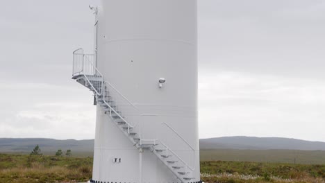Tilting-shot-of-a-wind-farm-turbine,-its-blades,-the-tower-and-the-base