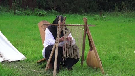 Recreación-Vikinga-Hombre-Tejiendo-Sentado-En-Una-Silla-Tradicional-En-Woods-Town-Waterford,-Irlanda