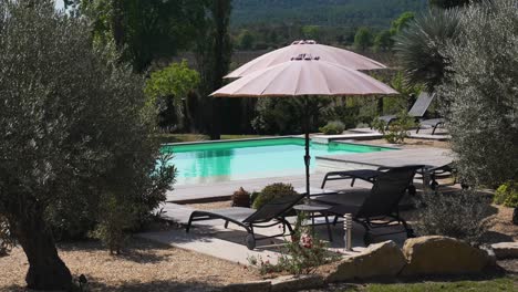 Slow-establishing-shot-of-sun-loungers-with-parasols-alongside-a-private-pool-on-Nimes