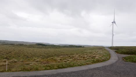 Wide-angle-shot-of-two-wind-turbines-along-a-dirt-track-on-the-Hebrides