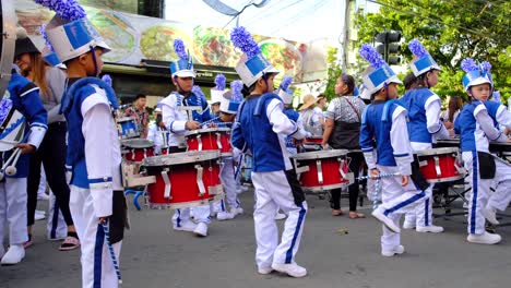 Gruppe-Junger-Musiker-In-Blau-weißer-Uniform,-Die-Bei-Einer-Straßenparade-Mit-Trommeln-Musik-Spielen