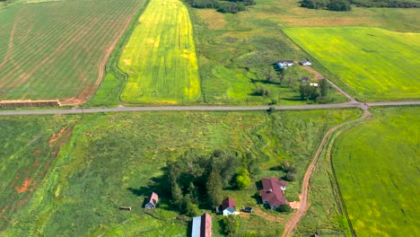Ländliche-Ackerlandhäuser,-Die-Zwischen-Feldern-Und-Einem-Sich-Schlängelnden-Fluss-Am-Rande-Von-Bozeman-Montana-Gebaut-Wurden,-Luftpanorama