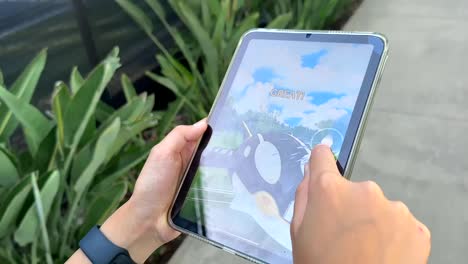 POV-Of-Child-Playing-Pokemon-Go-On-A-Mobile-Tablet-While-Walking-Through-The-Neighborhood-Park