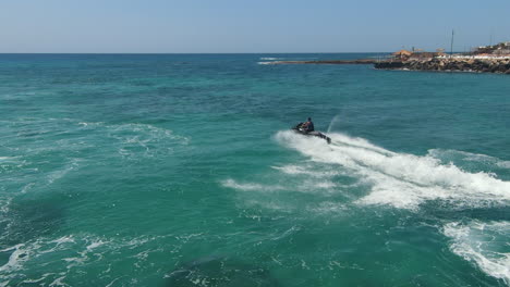 Wave-rider's-perspective,-droning-above-jet-skiing-on-the-ocean-in-slow-motion