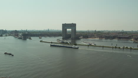 Barcaza-Navegando-Por-El-Río-Ij-Pasando-Por-El-Hotel-Pontsteiger-En-Amsterdam,-Países-Bajos