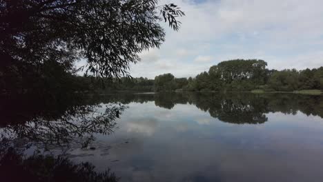 Schwenken-Mit-Blick-Auf-Einen-Noch-Spiegelnden-See-In-Einem-Wald-In-England