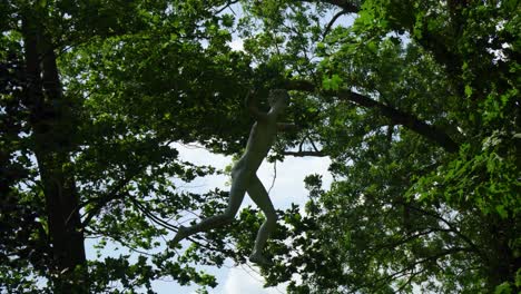 statue-of-a-young-male-flying-and-spinning-in-the-air-in-between-the-trees-looking-mystical-and-very-random-scary-zooming-in-towards-the-sculpture-city-project-hanging-on-invisible-strings-strange