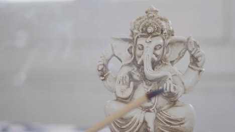 Close-up-of-a-Ganesha-figurine-behind-a-burning-incense