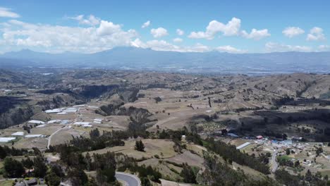 Breathtaking-4K-drone-flight-capturing-Saquisilí-City-valley-in-Cotopaxi-Province,-Ecuador,-with-Cotopaxi-and-Rumiñahui-volcanoes-against-blue-skies-and-drifting-clouds