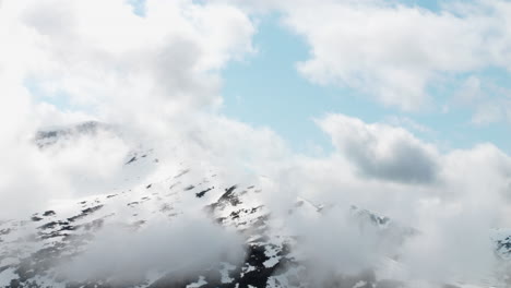 Clouds-surrounding-mountain-range-with-snow