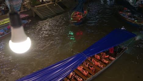Motorized-wooden-boats-moving-from-the-right-to-the-left-side-of-the-frame-are-cruising-along-the-canals-of-Amphawa-Floating-Market-in-Samut-Songkhram,-Thailand