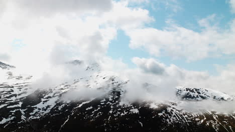 Clouds-surrounding-mountain-range-with-snow