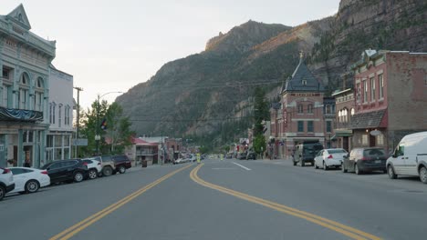 Blick-Auf-Die-Hauptstraße-In-Ouray,-Colorado,-Mit-Vorbeiströmendem-Verkehr-Während-Der-Goldenen-Stunde-Und-Den-San-Juan-Bergen-Im-Hintergrund