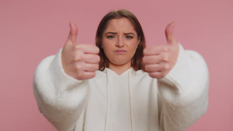 Upset-woman-in-white-sweater-showing-thumbs-down-sign-gesture,-disapproval,-dissatisfied-dislike