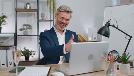 Business-man-working-on-laptop-celebrate-successful-contract-agreement-with-colleague-at-office