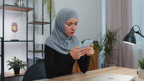 Mujer-De-Negocios-Musulmana-Usa-Un-Teléfono-Inteligente-Sorprendida-Por-Resultados-Repentinos-De-Lotería,-Malas-Noticias,-Pérdida-De-Fortuna,-Fracaso