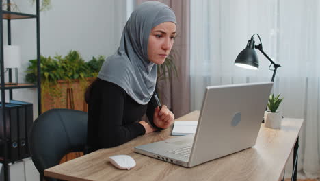 Muslimische-Geschäftsfrau-Studiert-Mit-Notebook-Im-Heimbüro-Am-Laptop-Und-Spricht-Online-Mit-Der-Webcam