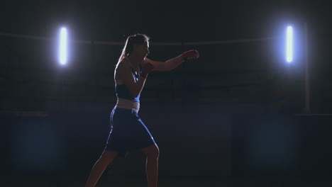 A-strong-athletic,-woman-boxer,-boxing-at-training-on-the-black-background.-Sport-boxing-Concept-with-copy-space.