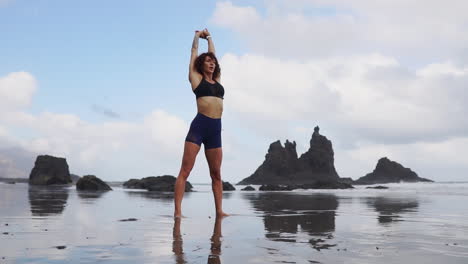 Slow-motion-captures-a-young,-slender-woman's-serene-moment,-as-she-practices-stretching-and-yoga-by-the-ocean,-her-gaze-extending-into-the-distance