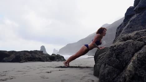 Slow-motion-captures-a-slim,-young-female-athlete-doing-push-ups-on-a-seaside-rock