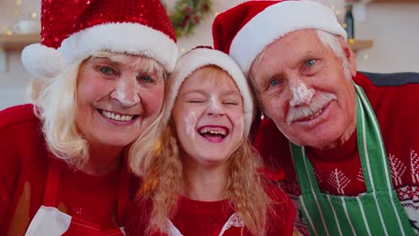 POV-of-senior-grandparents-with-granddaughter-kid-taking-selfie-on-mobile-phone-on-Christmas-kitchen