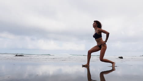 Engaging-in-relaxing-exercises-by-the-sea,-a-female-athlete-joins-a-fitness-woman-in-leg-stretches-or-lunges-on-the-beach,-all-in-slow-motion