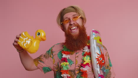 Traveler-tourist-young-hippie-man-celebrating,-dancing-fooling-with-swimming-inflatable-duck-toy