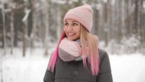 Woman-in-a-jacket-and-hat-in-slow-motion-looks-at-the-snow-and-catches-snowflakes-smiling