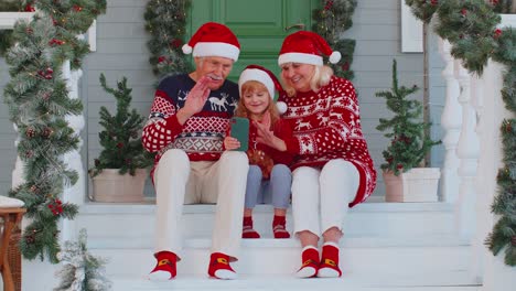 Grandparents-family-with-granddaughter-taking-selfie-on-mobile-phone,-video-call-online,-Christmas